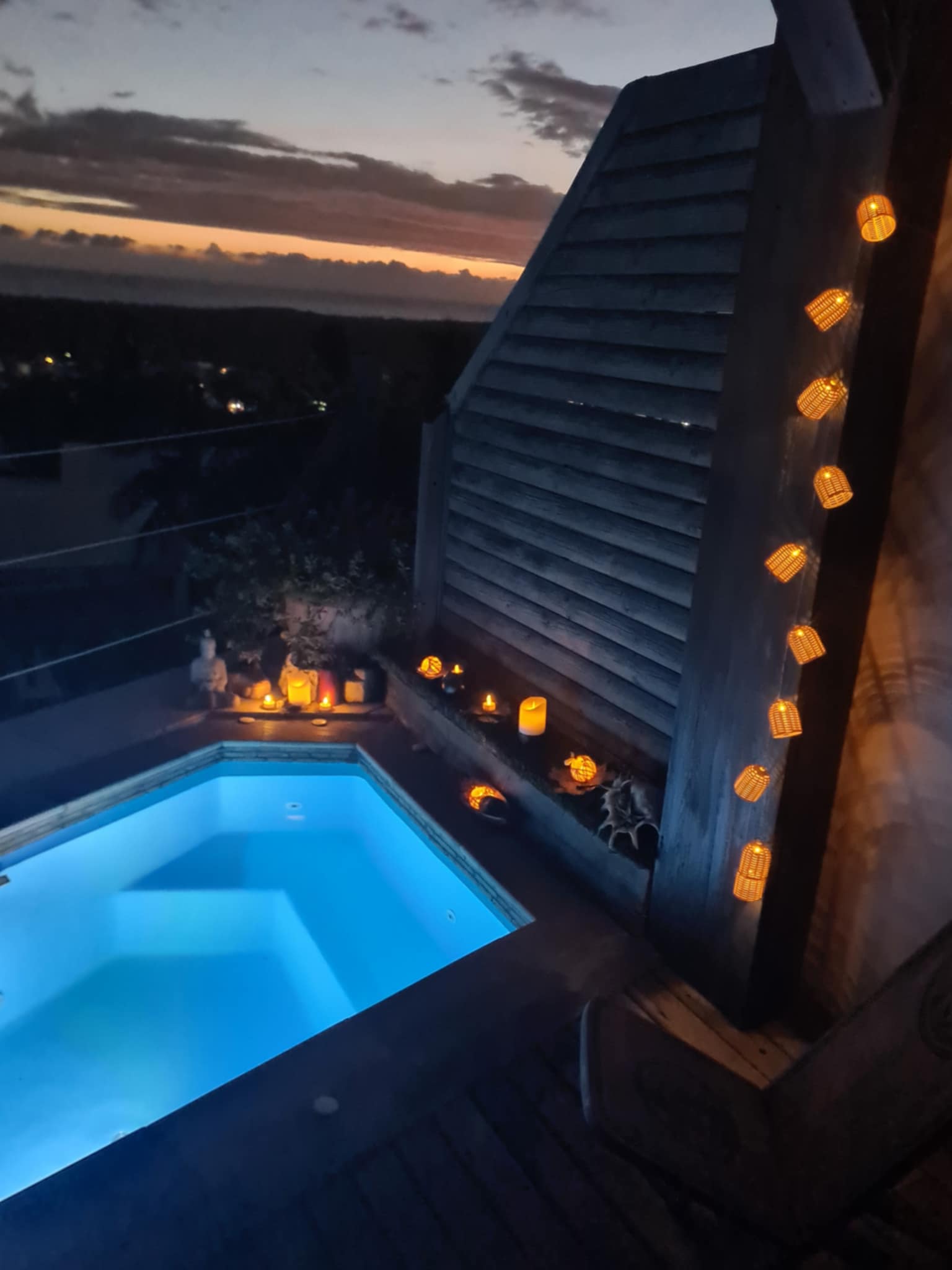 Jacuzzi illuminé au coucher du soleil avec guirlandes